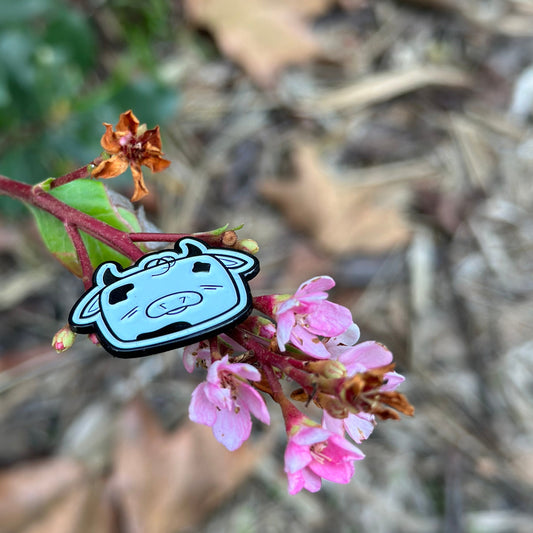 Small cartoon character attached to a pink flower with a blurred natural background